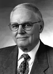Ray Marshall, PhD This is a black and white picture of Ray Marshall. He has gray hair and is wearing thin-framed glasses. He is wearing a suit and tie.