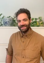 This is an image of David McCoy, a Social Science Research Associate at the Ray Marshall Center at the University of Texas at Austin.  He has a light complexion, dark brown hair and beard, and is smiling.
