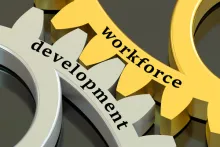 This is a closeup picture of two gears with "workforce" written on the gold one on the top and "development" written on the silver one on the bottom.