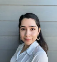 This is a headshot of Abigail Garza, M.Ed.  She has dark hair and a medium complexion.  She is wearing a light colored shirt and dangle earrings.  She is smiling.
