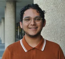 This is a photo of Adriel Bustillos.  He has a medium complexion with short dark hair, and he is wearing a burnt orange polo-style shirt.