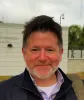 This is a close-up of Heath Prince, a Research Scientist at the Ray Marshall Center at the University of Texas at Austin. He has a light complexion, dark hair, gray beard, and is smiling.