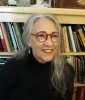 This image is a close-up of Cynthia Juniper, a Research Associate at the Ray Marshall Center at the University of Texas at Austin.  She has a light complexion, gray hair, red glasses, and is smiling.
