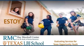 This is an image of young adult workers on a construction site.  There are five women dressed in matching dark blue shirts holding various construction tools and hard hats.
