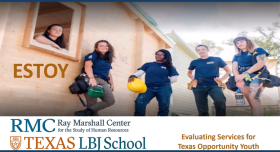 This is an image of young adult workers on a construction site.  There are five women dressed in matching dark blue shirts holding various construction tools and hard hats.