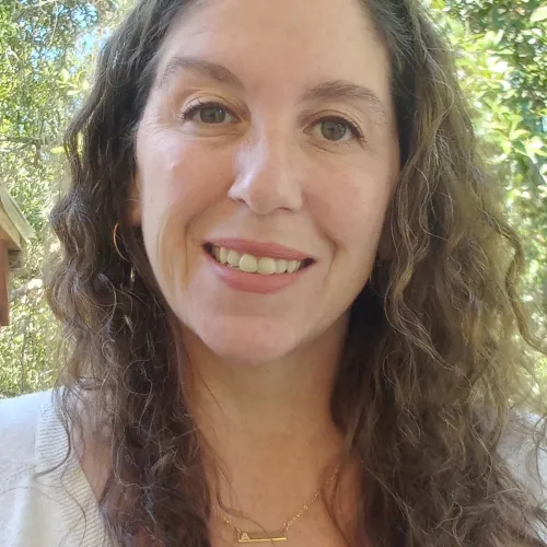 This is an image of Alanna Burney, a Senior Research Program Coordinator at the Ray Marshall Center at the University of Texas at Austin.  She has a light complexion, long curly brown hair, and is smiling.