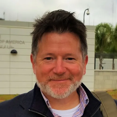 This is a close-up of Heath Prince, a Research Scientist at the Ray Marshall Center at the University of Texas at Austin. He has a light complexion, dark hair, gray beard, and is smiling.