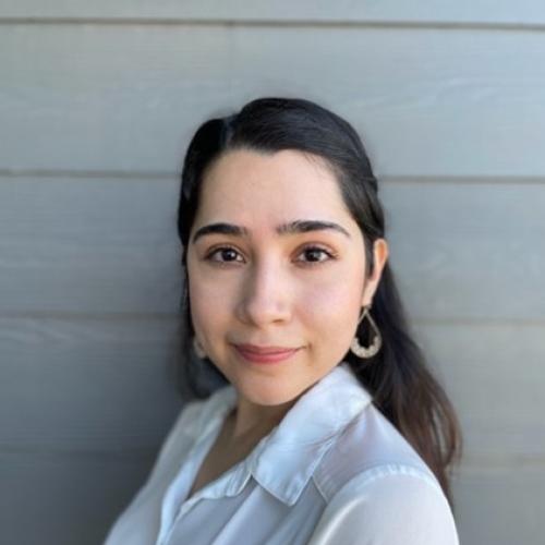 This is a headshot of Abigail Garza, M.Ed.  She has dark hair and a medium complexion.  She is wearing a light colored shirt and dangle earrings.  She is smiling.
